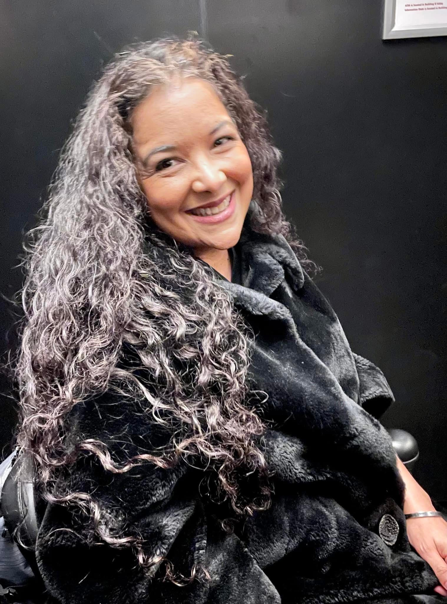 Mia Perez-Arroyo smiling, seated in a dark coat
